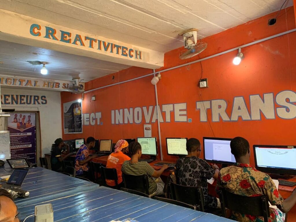 Wide view of the CIJ Digital Hub training room with rows of computers and the blue-and-orange painted walls