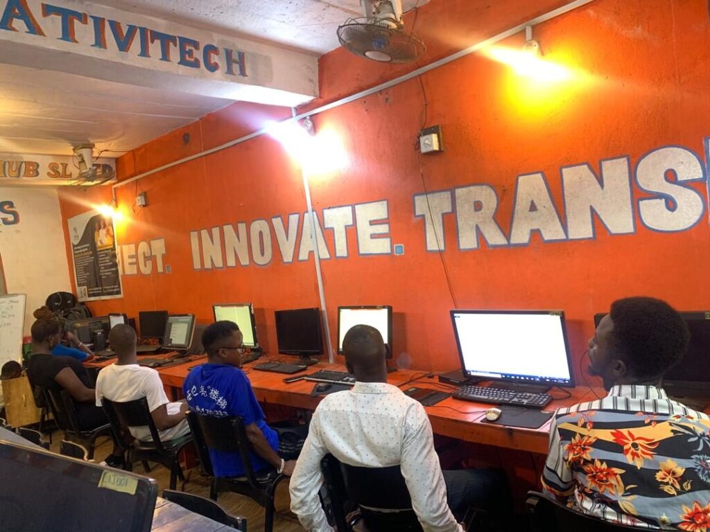 Learners at computers beneath the 'Connect. Innovate. Transform.' wall inside the CIJ hub