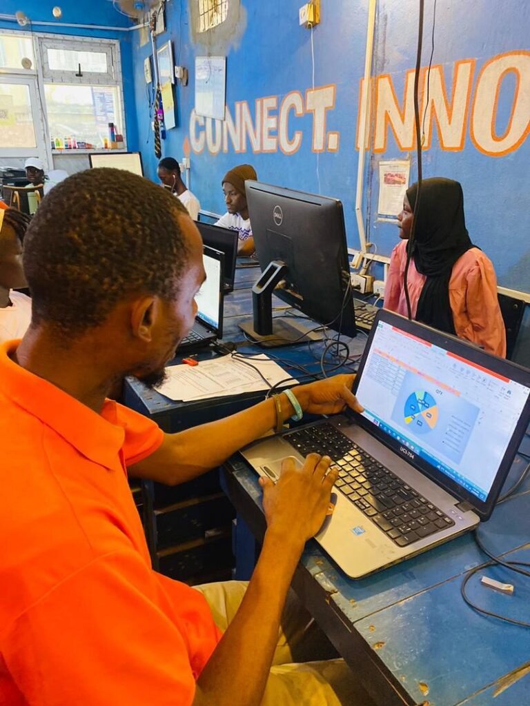 A mentor pointing at a laptop screen while a learner works