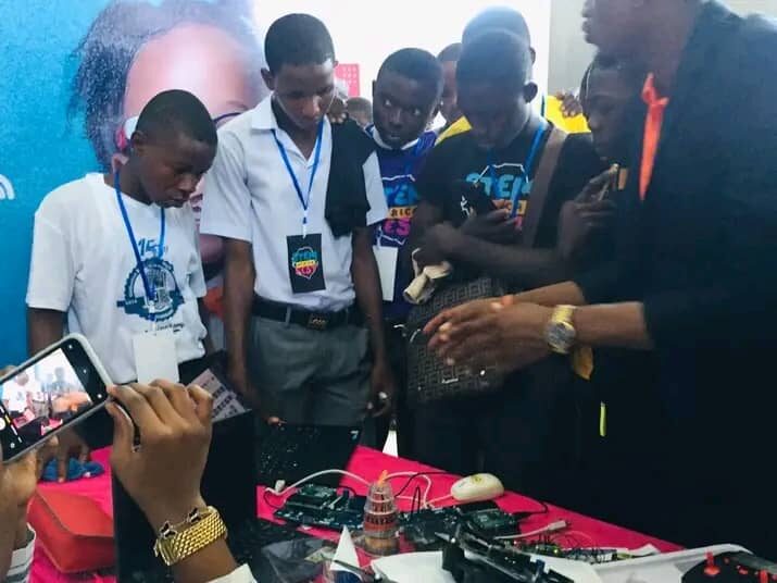 Secondary-school students in uniform examining an electronics kit at a STEM event