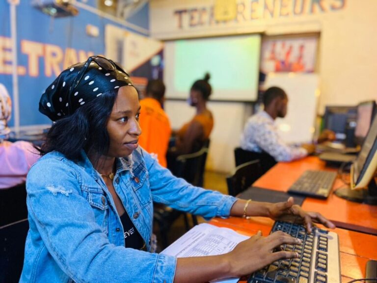 A trainer in a denim jacket helping a young man at a computer